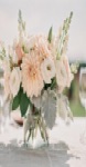 Blush and ivory wedding centerpiece in a glass vase on a linen table