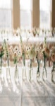 A row of small glass vase arrangements down a long banquet table